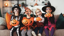 Bambini con addosso costumi di Halloween e con in mano dei recipienti a forma di zucca di Halloween