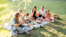 Persone riunite a mangiare all'aperto in occasione di un picnic