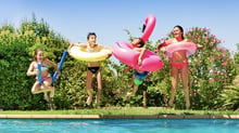 Persone che partecipano a un party in piscina e si tuffano in acqua con i salvagenti.