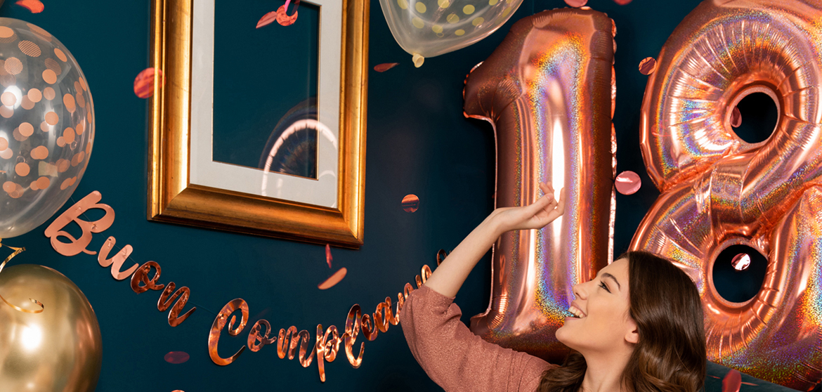 Una ragazza che guarda i palloncini Rose Gold a forma di numero 18