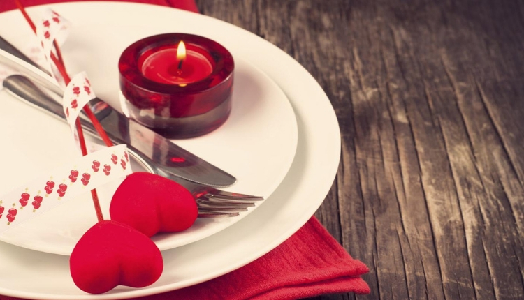 Dettagli di un'apparecchiatura a tema San Valentino con una piccola candela rossa