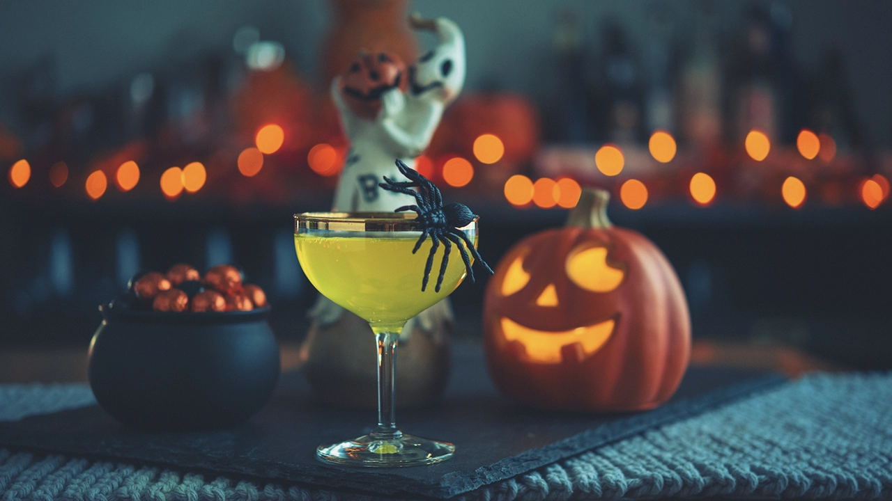 Drink decorato in stile Halloween con un ragnetto finto vicino a una zucca di Halloween